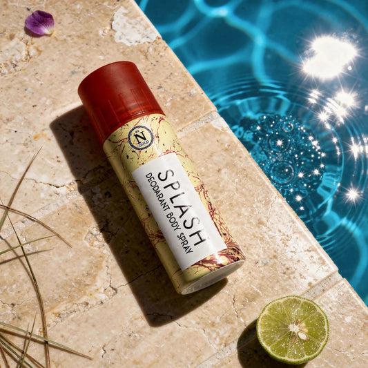 Deodorant body spray bottle labeled 'Splash' by a poolside with a lime and purple flower.
